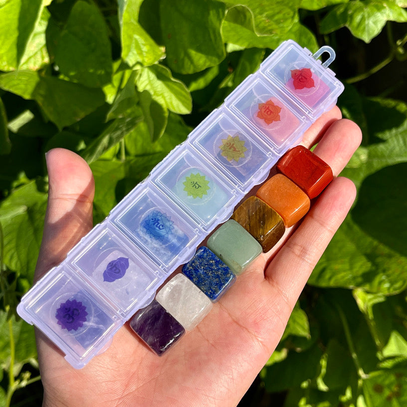 7 chakra crystal stones displayed in a plastic box with individual compartments and chakra symbols.