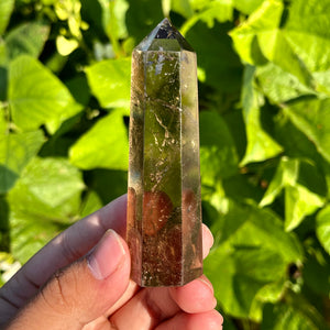 Three hand-carved smoky quartz towers with natural clarity and internal inclusions, displayed on a palm.