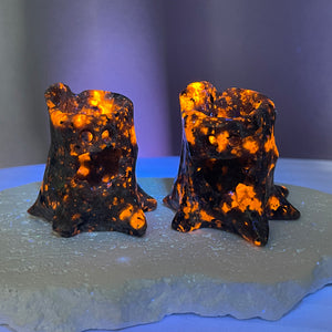 Glow-in-the-dark Yooperlite treant carvings glowing orange under UV light, set on a crystal base.