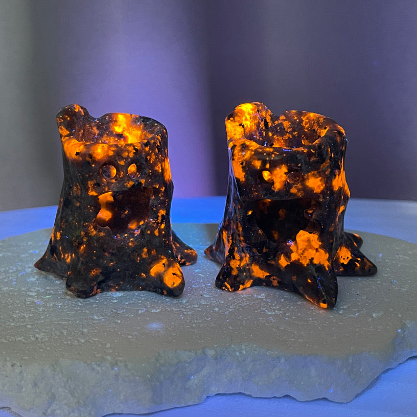 Glow-in-the-dark Yooperlite treant carvings glowing orange under UV light, set on a crystal base.