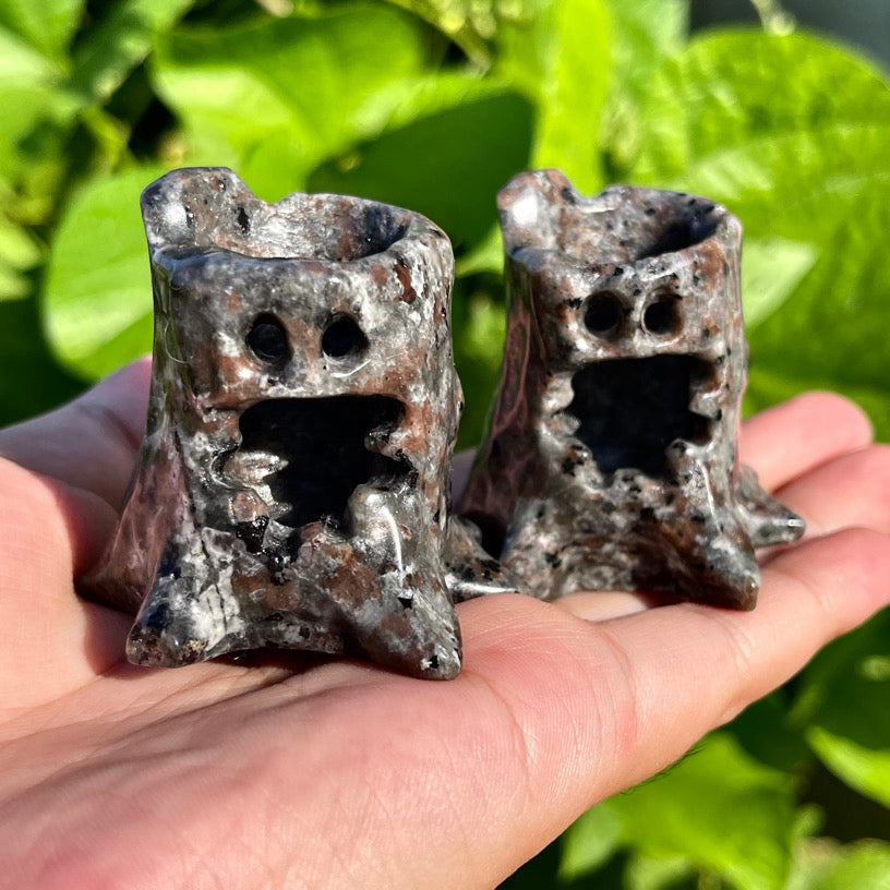 Pair of Yooperlite crystal carvings shaped like treants, glowing orange under blacklight on display.