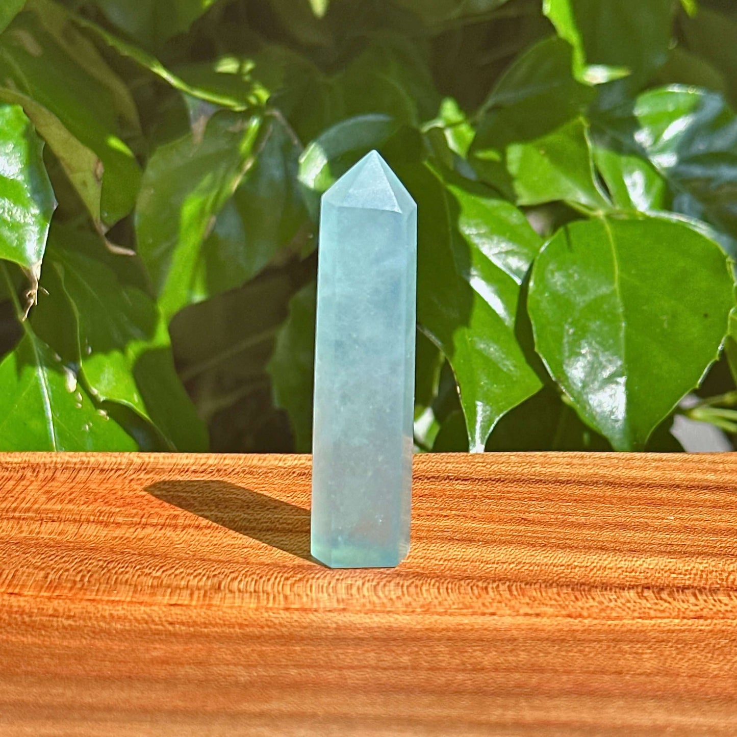 Aquamarine crystal tower displayed in natural light, showcasing its calming blue and green hues.