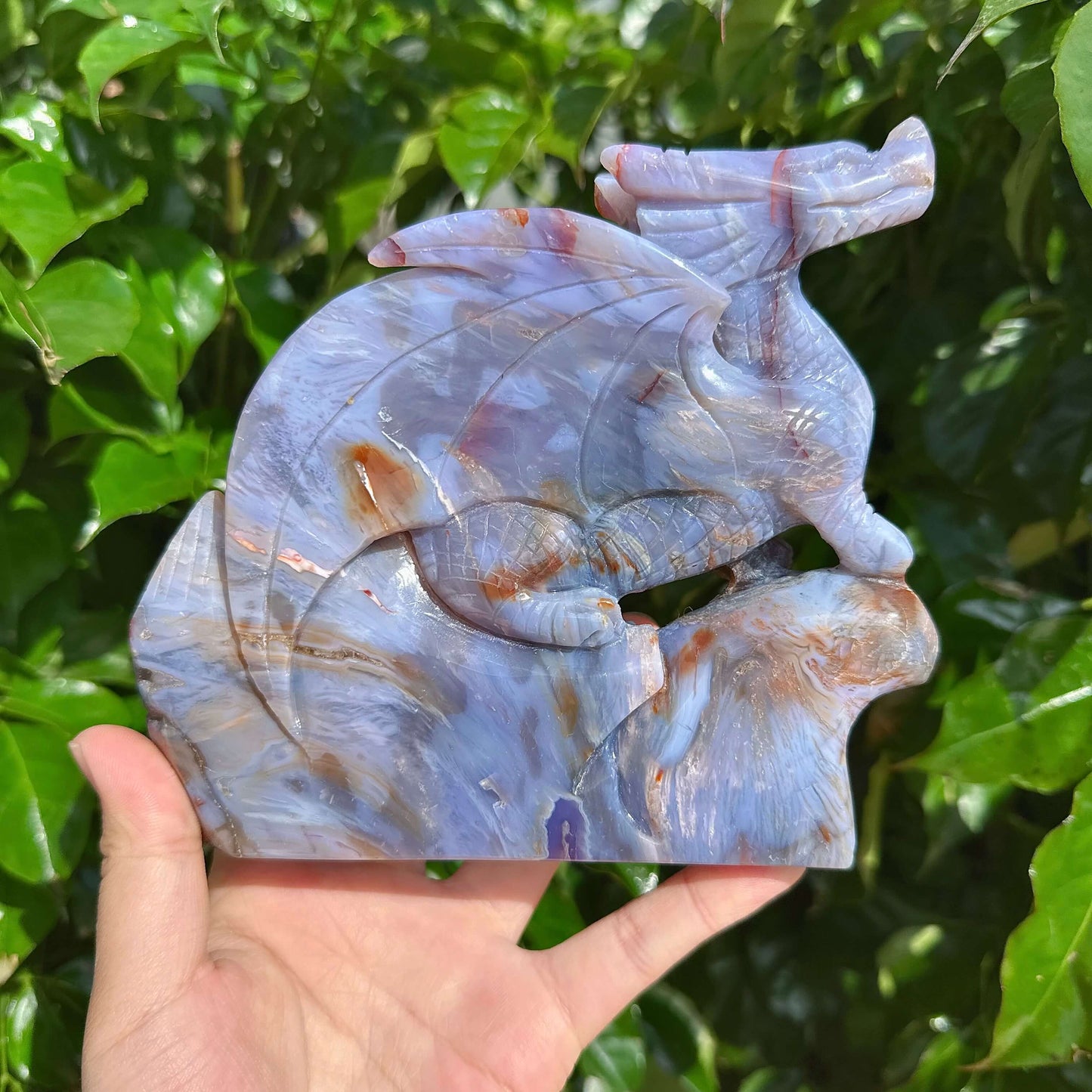 Hand holding Blue Flower Agate Dragon Carving displaying its vibrant colors and details.