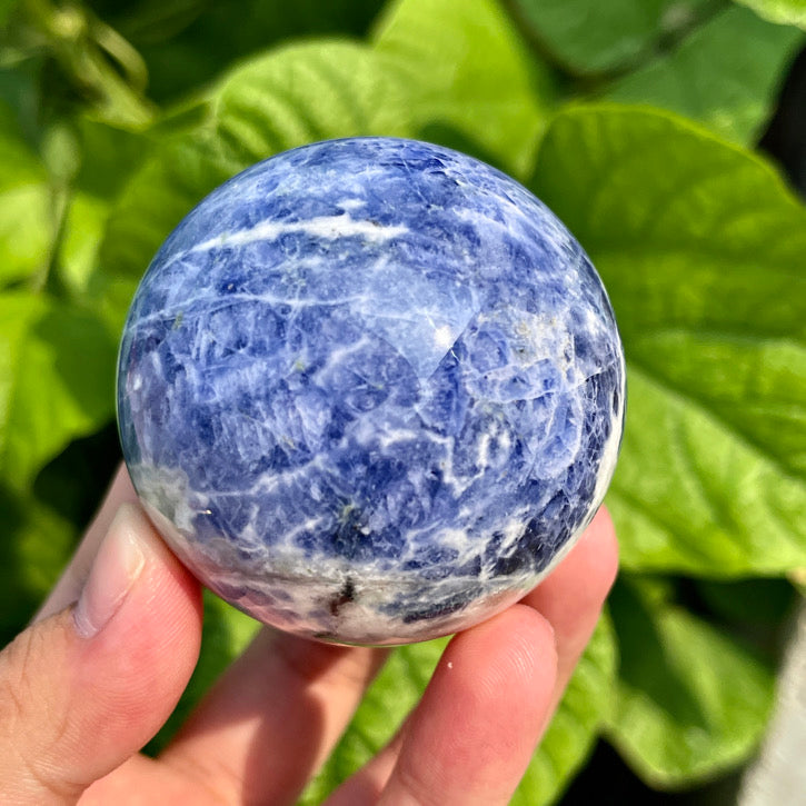 Natural sodalite crystal sphere with dark indigo and white streaks