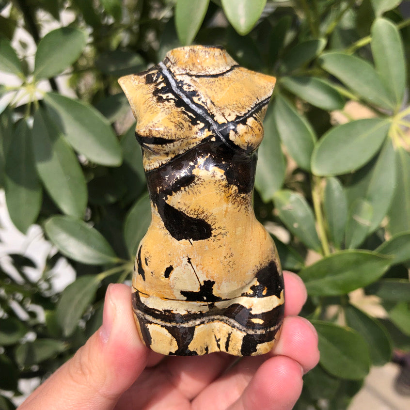 Hand holding a Picture Jasper body model sculpture with natural black and beige patterns.