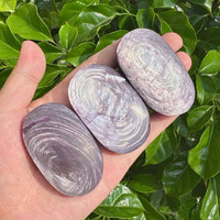 A smooth and polished Lepidolite Palm crystal showing calming shades of purple and pink, perfect for promoting relaxation and balance.