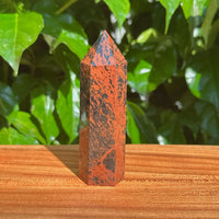 Hand-held Mahogany Obsidian Tower displaying a natural dark and reddish finish, ideal for meditation and healing spaces.