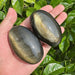 Golden Obsidian Palm Stone with a smooth surface reflecting light and rich dark hues.
