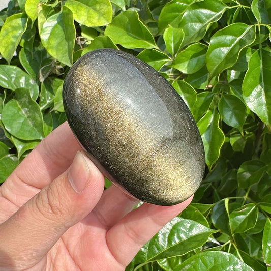 Side view of a Golden Obsidian Palm Stone, featuring metallic gold streaks that catch the light beautifully.