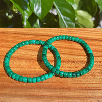 Malachite bracelet worn on wrist, displaying its polished green beads for personal well-being and emotional strength.