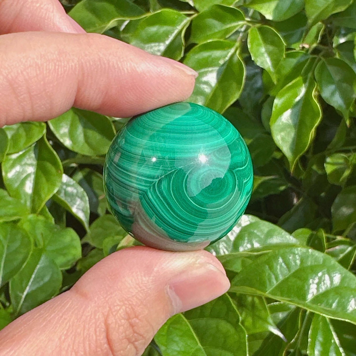 Polished malachite sphere with vivid green hues and smooth surface