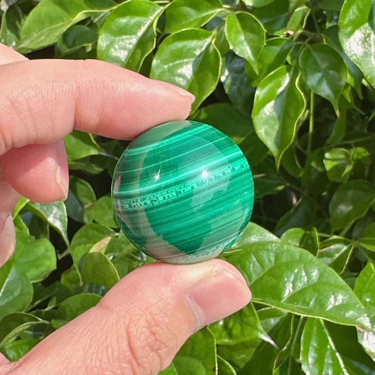 Natural malachite sphere showing distinct green patterns and glossy shine