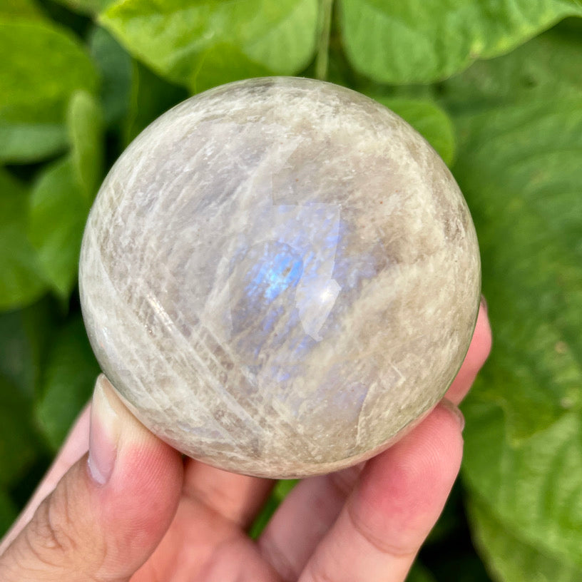 Crystal ball made of natural rainbow moonstone, featuring shimmer and iridescent reflection.