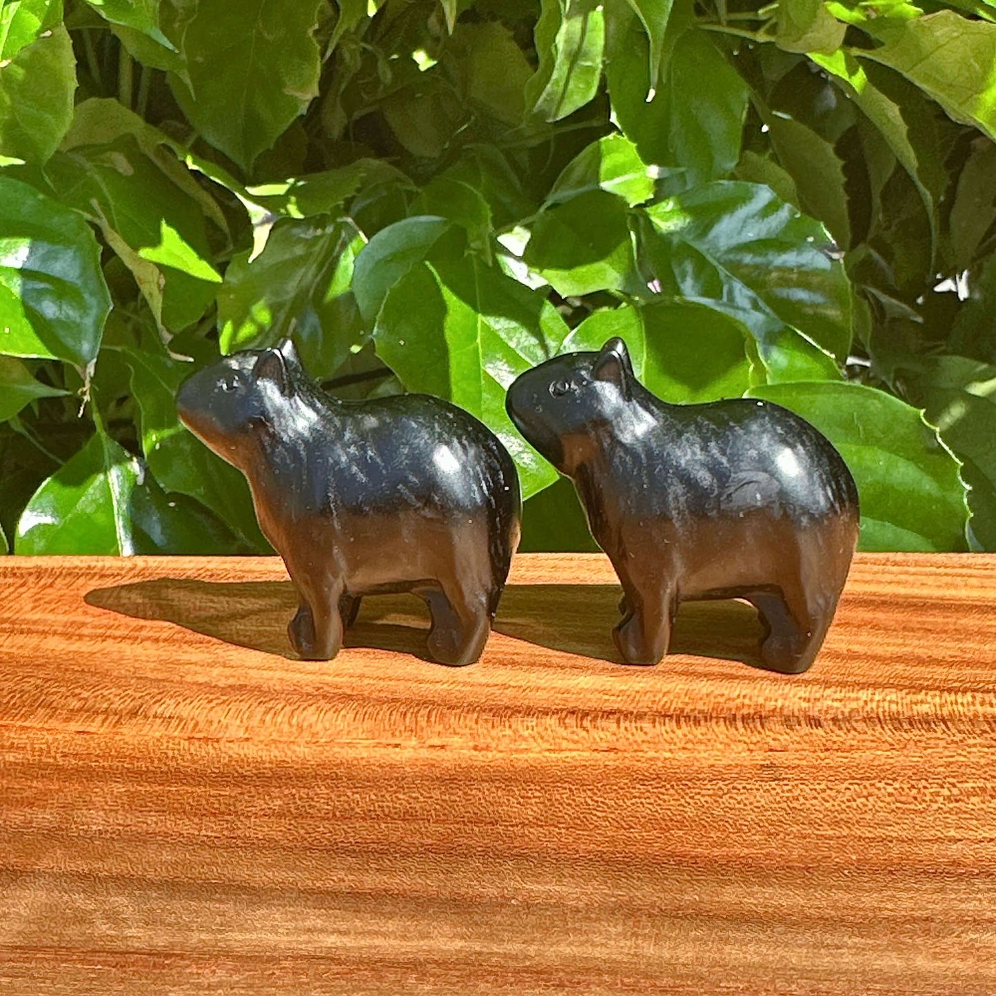 Close-up of the Obsidian Kapibala figurine being held in hand, showcasing the craftsmanship and the smooth, glossy surface that reflects the natural beauty of the obsidian material.