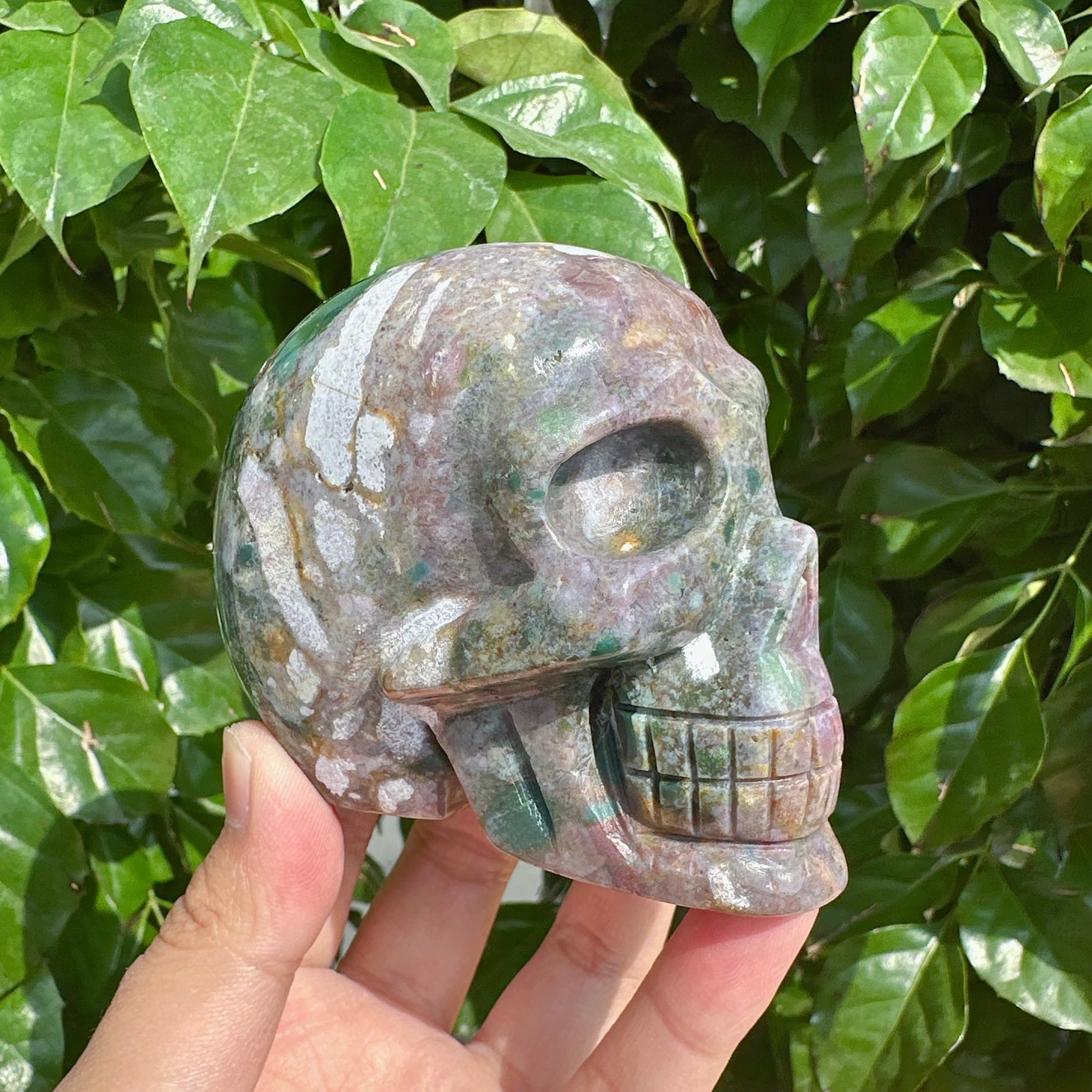 A person holding the Ocean Jasper skull carving, showcasing its size and exquisite gemstone features.