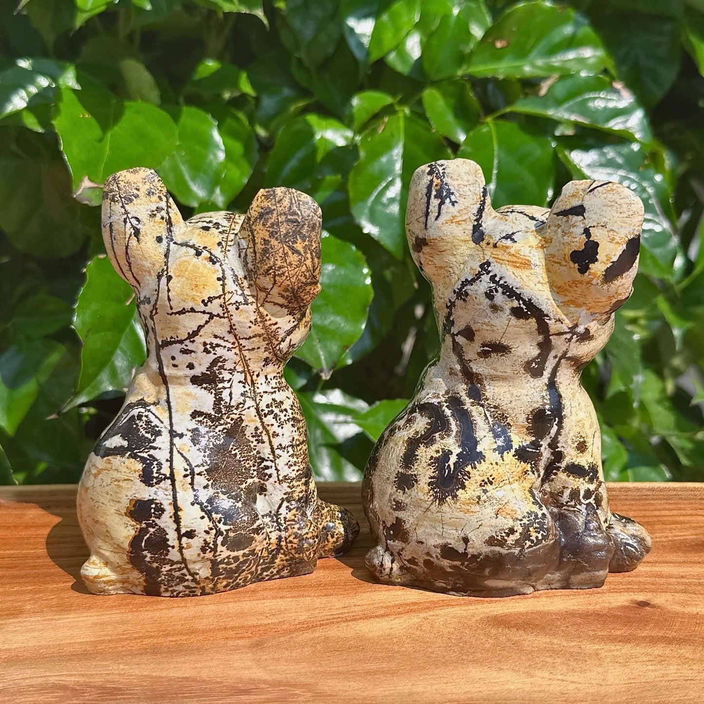 Close-up of two Picture Jasper French Bulldog carvings with natural color patterns.