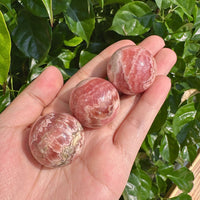 Rhodochrosite Sphere reflecting light with rich pink tones