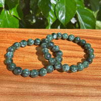 Close-up view of Seraphinite bracelet with smooth green gemstones, perfect for energy healing and chakra balancing.