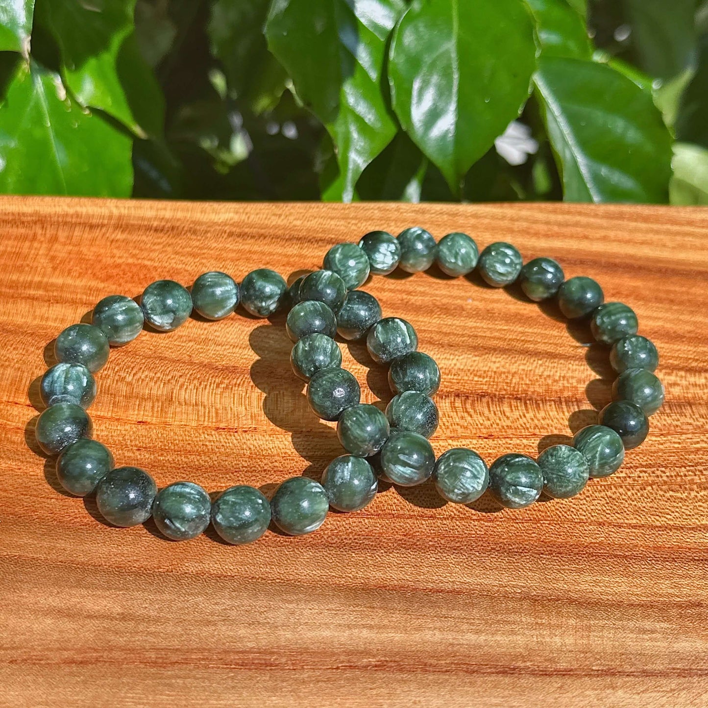 Close-up view of Seraphinite bracelet with smooth green gemstones, perfect for energy healing and chakra balancing.