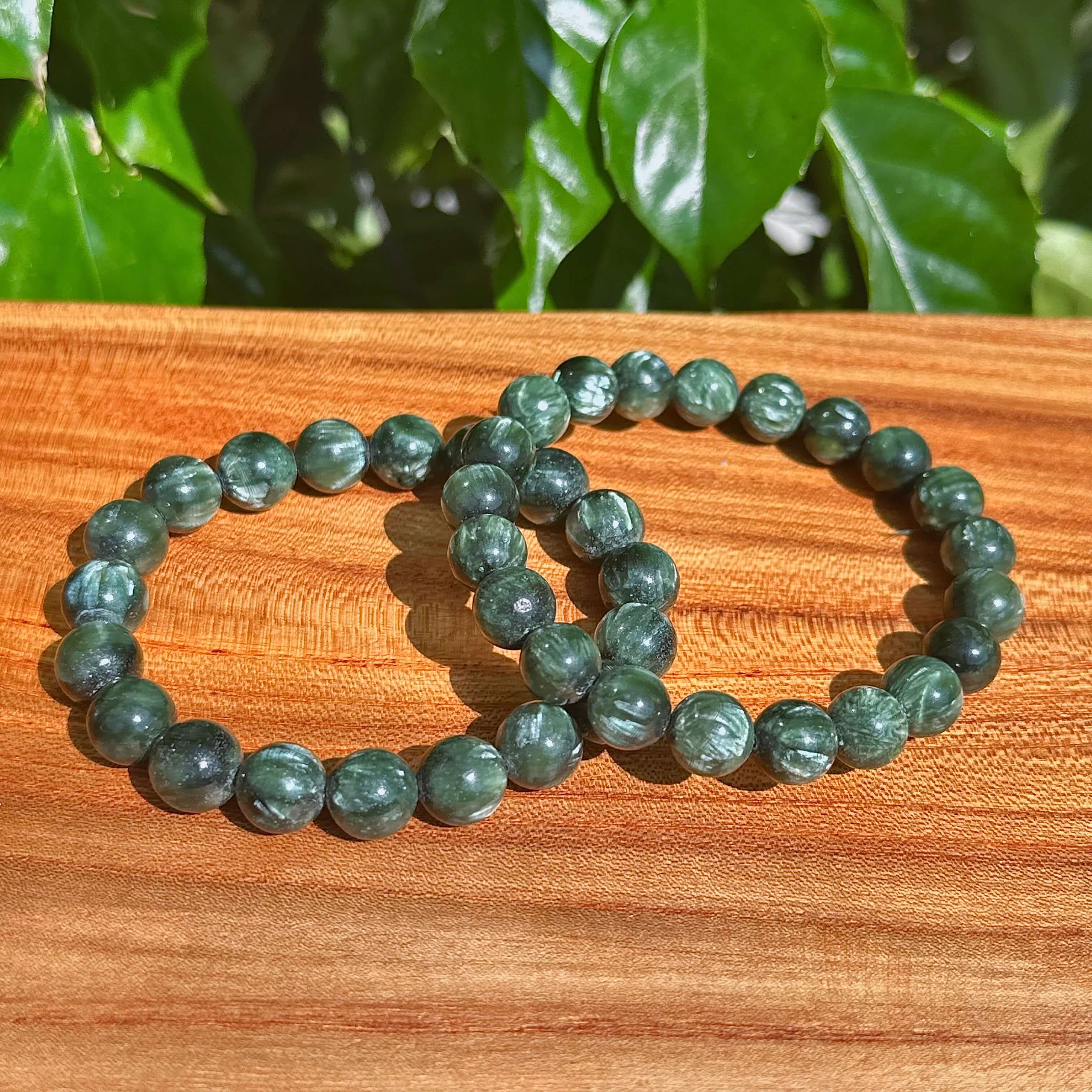 Close-up view of Seraphinite bracelet with smooth green gemstones, perfect for energy healing and chakra balancing.