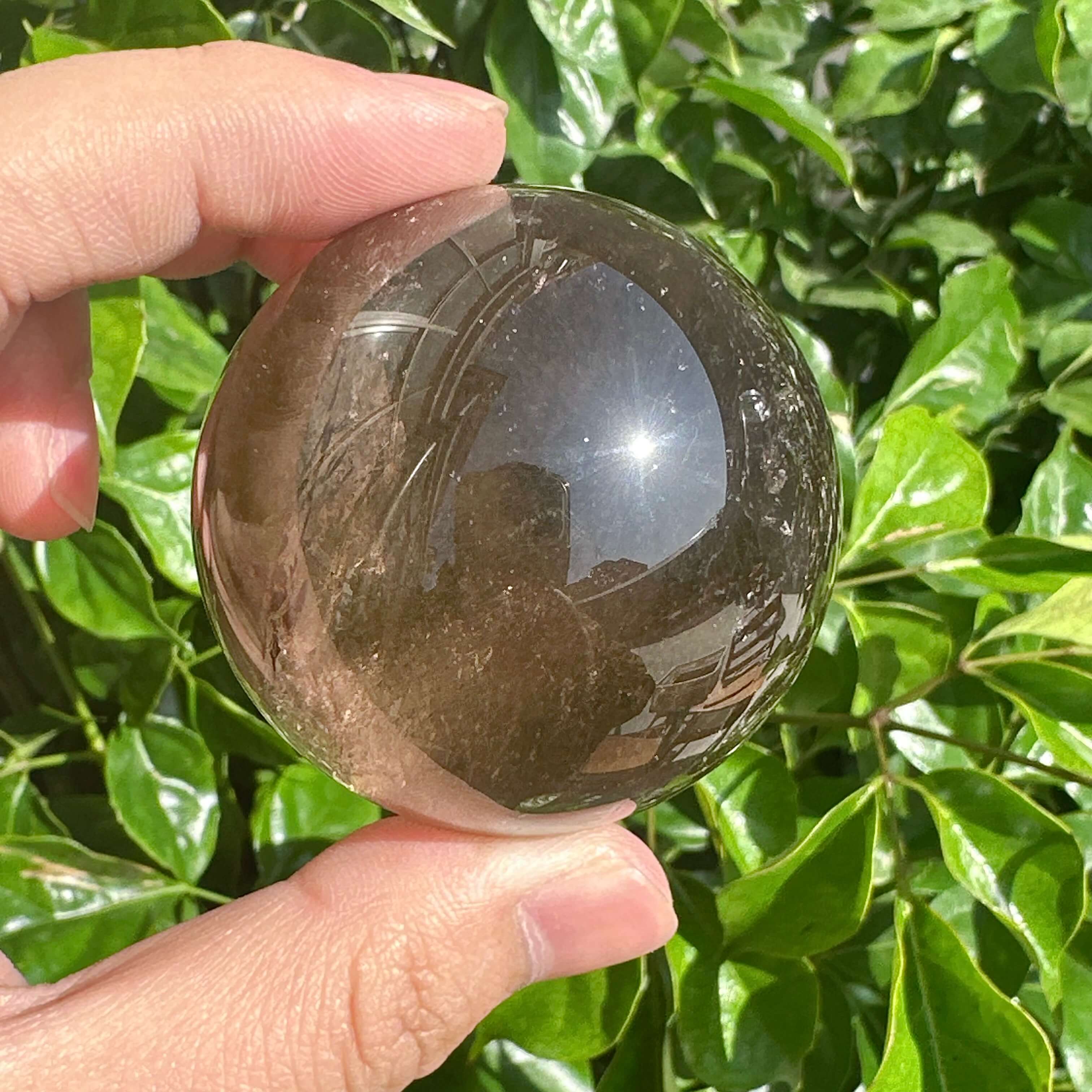 Close-up of Smoky Quartz Sphere reflecting light, showcasing its unique formation and grounding healing qualities.