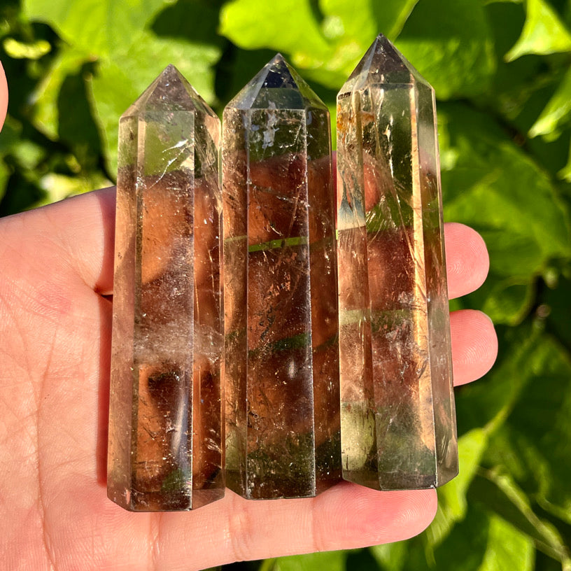 Smoky quartz crystal points featuring transparent brown tones and light-reflecting surfaces.  